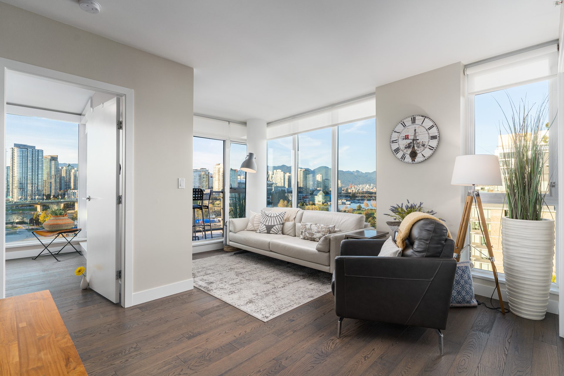 Living room at 1107-288 West 1st Avenue with corner windows overlooking downtown Vancouver and the North Shore mountains