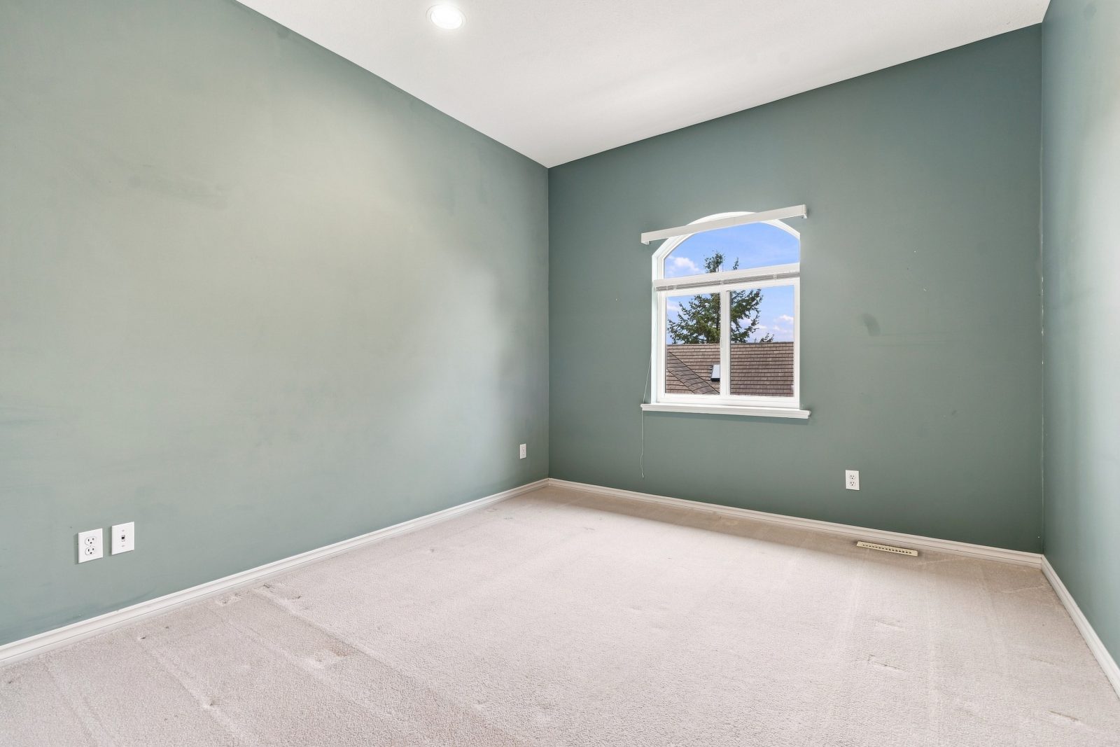 Secondary bedroom with arched window and carpet at #11 915 Fort Fraser Rise