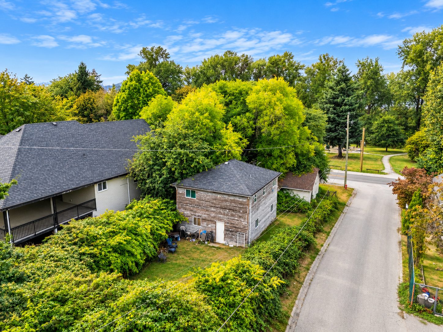 Aerial view of the home and rear structure at 13090 111 Avenue among mature trees in Whalley, Surrey
